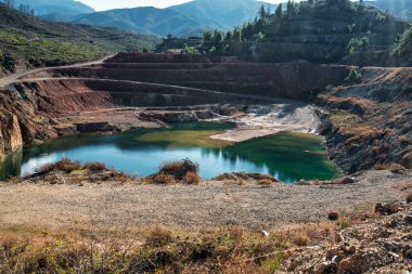 Yunanistan 'ın Evia kentindeki çarpıcı yapay göl, katmanlı kaya oluşumları, kırmızı renkli uçurumlar, dağınık çam ağaçları ve uzak dağlarla çevrili..