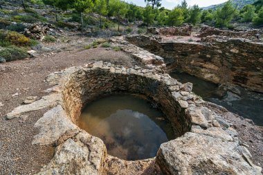 Yunanistan 'ın Lavrion kentinde taş yapılar, kazı çukurları ve çevreleyen yeşil arazilerin yer aldığı antik gümüş madencilik sahasının kalıntıları.