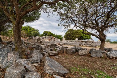 Yunanistan 'ın Ramnous kentindeki Nemesis antik Sığınağı' nın dağılmış taş kalıntıları, ağaçlarla çevrili ve Ege manzarasına bakan.