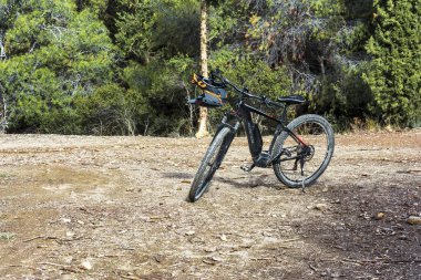 Attica, Yunanistan - 1 Aralık 2024: Hymettus dağ ormanında kirli bir yolda duran elektrikli dağ bisikleti, açık hava bisikleti ve doğa keşfi için mükemmel.
