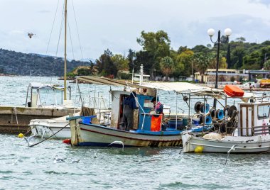 Nea Peramos, Yunanistan - 16 Şubat 2025: Nea Peramos limanında sakin deniz, martılar ve kıyı manzarasıyla çevrili balıkçılarla demirlemiş geleneksel balıkçı tekneleri.