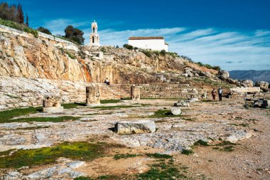 Eleusis, Yunanistan - 2 Şubat 2025: Eleusis 'teki Ploutonion mağarası sığınağı, yukarıda Panagia Kilisesi ve antik basamaklarda oturan bir turist ile yeraltı efsaneleriyle bağlantılı..