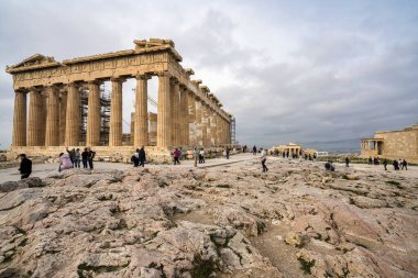 Atina, Yunanistan - 2 Mart 2025: Yunanistan 'ın en ikonik antik tapınağı olan Parthenon, ziyaretçiler tarihi kalıntıları arasında yürürken Akropolis manzarasına hakim oluyor.