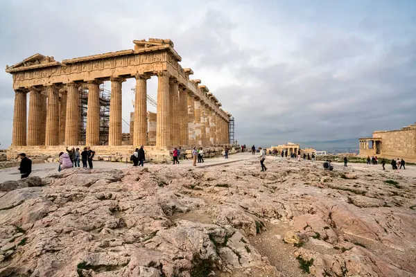 Atina, Yunanistan - 2 Mart 2025: Yunanistan 'ın en ikonik antik tapınağı olan Parthenon, ziyaretçiler tarihi kalıntıları arasında yürürken Akropolis manzarasına hakim oluyor.