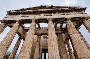 Atina 'nın Antik Agora' sındaki Hephaestus Tapınağı 'nın bulutlu gökyüzü altındaki Doric sütunlarına ve frizlerine bakıyorum..