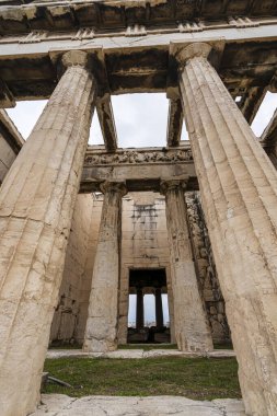 Atina 'nın Antik Agora' sındaki Hephaestus Tapınağı 'nın bulutlu gökyüzü altındaki Doric sütunlarına ve frizlerine bakıyorum..