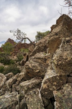 Sivri volkanik kayalar ve dağınık bitki örtüsü, Methana yarımadası kıyı şeridine bakan Kameno Vouno 'nun engebeli arazisine hakim..
