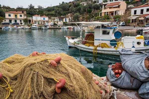 Methana, Yunanistan - 23 Mart 2025: Geleneksel balıkçı ağları Methana 'da sessiz bir Yunan limanının ön planında, arka planda tekneler ve rıhtım evleri bulunuyor.
