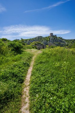 Bahar çimenleri boyunca uzanan patika, Osmanlı taş yapısını geçerek Ortaçağ Frankish Kulesi 'nin bulunduğu Akrokorintos zirvesine çıkıyor..