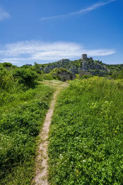 Bahar çimenleri boyunca uzanan patika, Osmanlı taş yapısını geçerek Ortaçağ Frankish Kulesi 'nin bulunduğu Akrokorintos zirvesine çıkıyor..