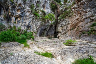 Yıpranmış kireçtaşı terasları gölgeli bir mağaraya açılıyor ve Yunanistan 'ın tenha Aziz Luke Geçidi' ndeki dokulu uçurumların altında hâlâ havuz var..