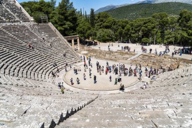 Epidaurus, Yunanistan - 11 Mayıs 2025: Turistler, MÖ 4. yüzyıl Yunan mimarisinin akustiği ve klasik tasarımı ile ünlü bir harikası olan Epidaurus Antik Tiyatrosu 'nun sahne ve koltuklarını keşfediyorlar..