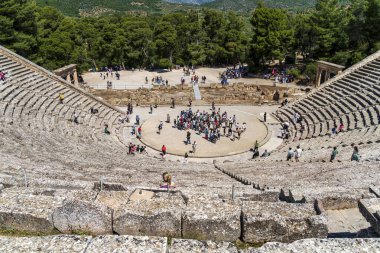 Epidaurus, Yunanistan - 11 Mayıs 2025: Turistler, MÖ 4. yüzyıl Yunan mimarisinin akustiği ve klasik tasarımı ile ünlü bir harikası olan Epidaurus Antik Tiyatrosu 'nun sahne ve koltuklarını keşfediyorlar..