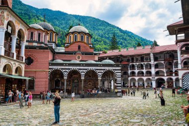 Rila Manastırı, Bulgaristan - 6 Ağustos 2025: Bulgaristan 'ın Rila Manastırı' nın avlusunda yürüyen ziyaretçiler, dağlarla çevrili bir UNESCO Dünya Mirası Alanı ve tarihi mimariyle çevrili.