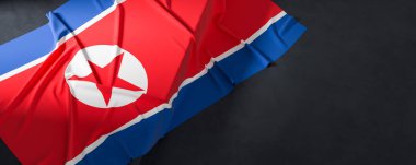 Kuzey Kore bayrağı. Kumaş desenli Kuzey Kore bayrağı koyu arka planda izole edilmiş. 3B illüstrasyon