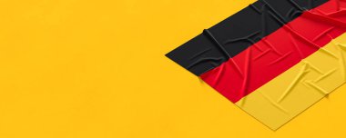 Almanya bayrağı. Kumaş desenli Alman bayrağı sarı arka planda izole edildi. 3B illüstrasyon