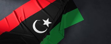 Libya bayrağı. Kumaş desenli Libya bayrağı koyu arka planda izole edildi. 3B illüstrasyon