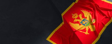 Karadağ bayrağı. Kumaş desenli Karadağ bayrağı koyu arka planda izole edildi. 3B illüstrasyon