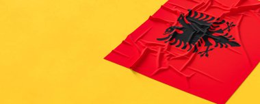 Arnavutluk bayrağı. Kumaş desenli Arnavutluk bayrağı sarı zemin üzerinde izole edilmiş. 3B illüstrasyon