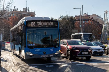 Madrid, İspanya. Kamu otobüsü hedefini gösteriyor Estacion Atocha, yoğun bir caddede gün ışığında şehir trafiğini takip ediyor.