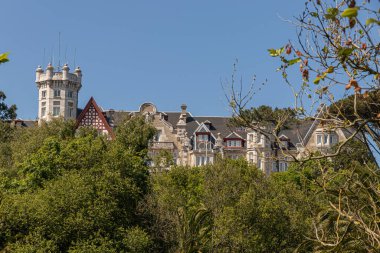 Santander, İspanya. Palacio de la Magdalena 'nın üst katları yoğun bir orman tepe örtüsünün üzerinde yükseliyor. Magdalena Yarımadası' nda açık bir bahar gökyüzü altında ele geçirildi.