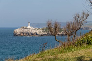 Santander, Cantabria, İspanya. 19. yüzyıldan kalma deniz feneriyle Mouro Adası 'nın uzak manzarası Cantabrian Denizi ile çevrili açık bahar gökyüzünün altında.