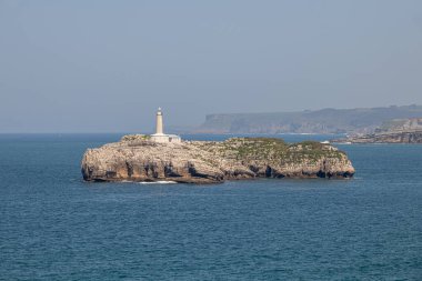 Santander, Cantabria, İspanya. 19. yüzyıldan kalma deniz feneriyle Mouro Adası 'nın uzak manzarası Cantabrian Denizi ile çevrili açık bahar gökyüzünün altında.