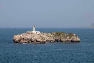 Santander, Cantabria, İspanya. 19. yüzyıldan kalma deniz feneriyle Mouro Adası 'nın uzak manzarası Cantabrian Denizi ile çevrili açık bahar gökyüzünün altında.