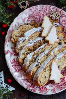 Christmas stollen with dried fruits, nuts and spices, Christmas decorations on a dark wooden background. Rustic style, selective focus.
