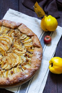 Tahta arka planda elma, ayva ve fındıkla doldurulmuş açık turta. Kırsal biçim, seçici odak.