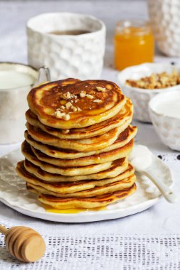 Apple pancakes served with honey, sour cream, nuts, tea and coffee. Rustic style, selective focus.