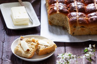 Cross buns served with butter, honey and tea. Easter breakfast, rustic style.