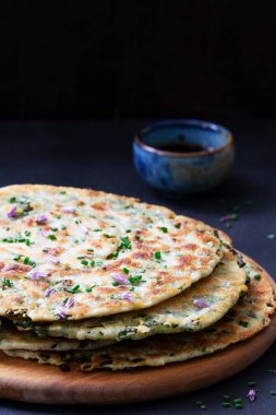 Homemade appetizing scallion pancakes served with soy sauce. Selective focus.