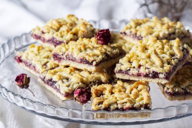 Frenk üzümlü streusel turta ve arka planda gül yaprağı var. Seçici odak, kırsal biçim.