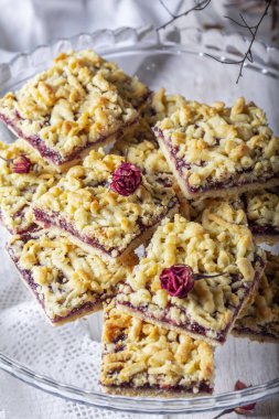 Frenk üzümlü streusel turta ve arka planda gül yaprağı var. Seçici odak, kırsal biçim.