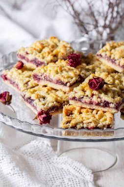 Frenk üzümlü streusel turta ve arka planda gül yaprağı var. Seçici odak, kırsal biçim.