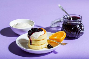 Ekşi kremalı şerbet ve leylak arkaplanda portakallı kuşüzümü reçeli kahvaltı. Seçici odak.