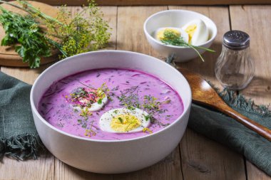 Geleneksel yaz soğuk pancar çorbası, salatalık, yumurta ve ekşi krema ve ahşap zemin. Kırsal biçim, seçici odak.