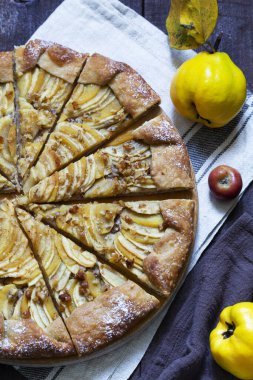Tahta arka planda elma, ayva ve fındıkla doldurulmuş açık turta. Kırsal biçim, seçici odak.