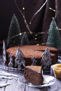 Chocolate honey cake in a Christmas decoration on a wooden background. Rustic style, selective focus.