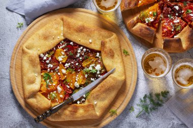 Geleneksel, domatesli, peynirli ve otlu turta galeti, bira veya şarapla servis edilir. Kırsal biçim, seçici odak.