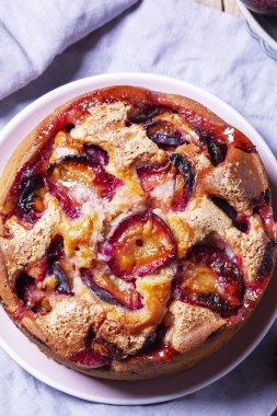 Doldurulmuş erik turtası ve şeker hamuru. Tahta bir masanın üzerine pudra şekeri ve erik serpiştirilmiş. Sonbahar durgun hayat, köy tarzı, seçici odaklanma.