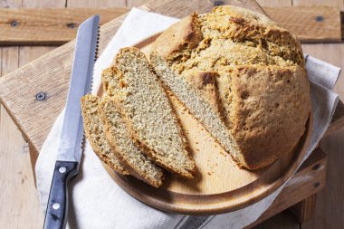 Ev yapımı İrlanda sodası ekmeği parçalara ayrılmış ve tahta zemin üzerinde bıçak var. Kırsal biçim, seçici odak.