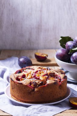 Doldurulmuş erik turtası ve şeker hamuru. Tahta bir masanın üzerine pudra şekeri ve erik serpiştirilmiş. Sonbahar durgun hayat, köy tarzı, seçici odaklanma.