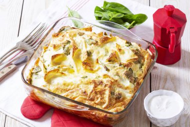 Traditional Bulgarian or Balkan pie banitsa made from filo dough, cream cheese and spinach, served with cream and coffee on wooden background. Rustic style, selective focus. clipart