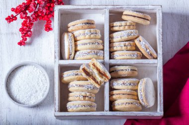 Alfajor, dolce de leche ile dolu kısa hamurlu pastadan yapılan geleneksel bir Latin Amerika kurabiyesi. Hafif bir arka planda Alfajores ve Noel dekoru.