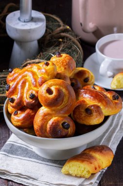 Traditional saffron Swedish buns lussekatt in different shapes, served with cocoa on a wooden table. Buns for St. Lucias Day. Rustic style, selective focus. clipart