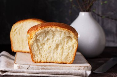 Ev yapımı sandviç mayalı ekmek. Tahta bir ışık panosunda ekmek ve gri arka planda bahar dalları olan bir vazo. Kırsal biçim, seçici odak.