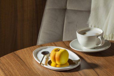 Şeftali dolgulu kremalı pasta kadife jöleli ve bir kafedeki masada bir fincan latte. Tatlı, içki, bir kafede ahşap masa, seçici bir odak..