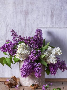 Açık arkaplanda bir buket leylak, odun parçaları ve böcekler. Bahar aylarında ahşap bir masanın üzerindeki leylak buketi gibi, kırsal tarzda, seçici bir odak noktası..